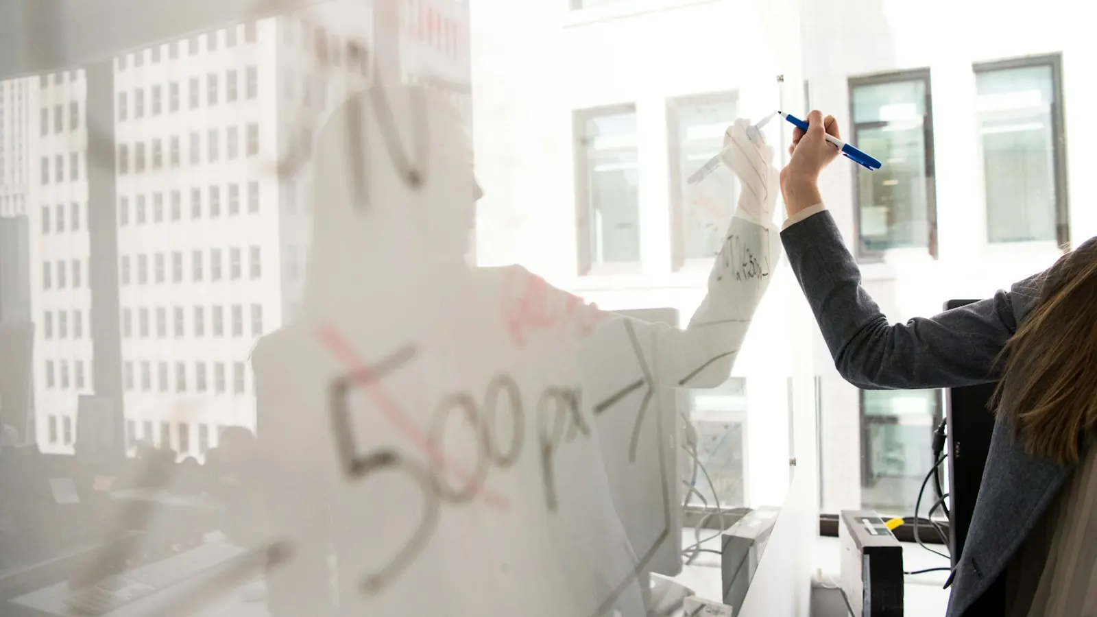 Person sketching on a glass whiteboard
